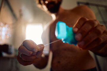 Close up of man cleaning his teeth with dental floss.