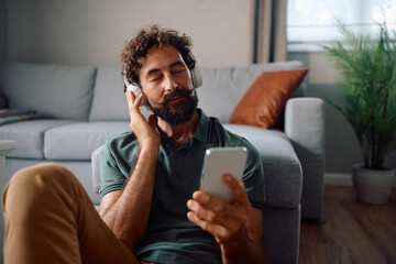 Mature man relaxing with music over headphones at home.