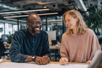Two co founders reviewing product prototypes on a desk, discussing ideas.