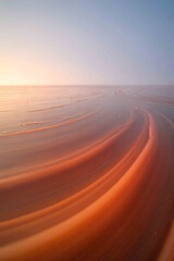 sunset over beach with smooth sand curves and ocean waves