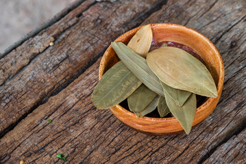 Dried bay leaves (Laurus nobilis) on wooden background. It is also known as Tej Pata, Cassia leaves, Cinnamomum tamala