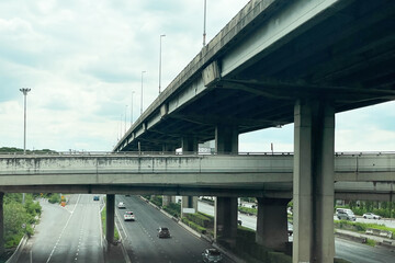 The intersection of the elevated expressway over the road in suburb area show smooth flow of traffic underneath. Image use for travel business and transportation industry background.