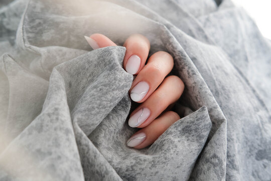 Beautiful women's manicure of milky color with silver stripes. Autumn design