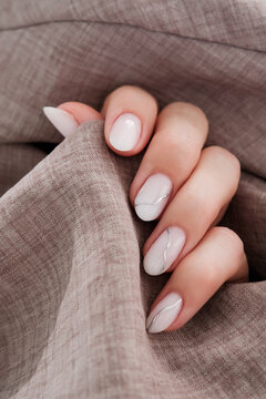 Beautiful women's manicure of milky color with silver stripes. Autumn design