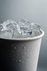 Refreshing ice water in a cup for hot summer days. Plastic cup with melting ice