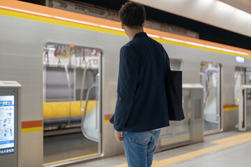駅のホームで電車を待つ男性