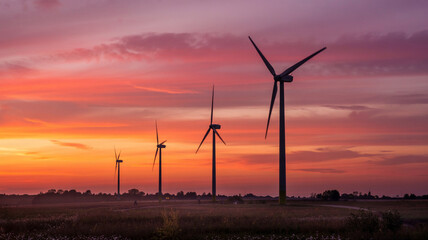 The sky ignites in colors as wind turbines gently tun in the evening breeze