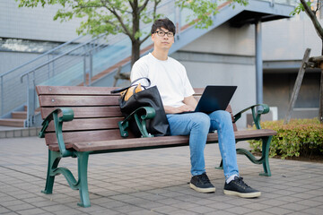 ベンチでパソコンを操作する男性