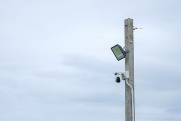 CCTV security camera on a pole with cloudy sky background, security concept