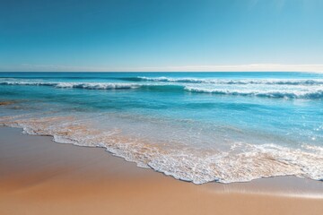 Fototapeta premium Sun-drenched beach meets turquoise ocean. Soft waves lap at the shore, under a clear blue sky