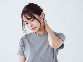 首の痛みを感じて手で押さえる表情の日本人女性