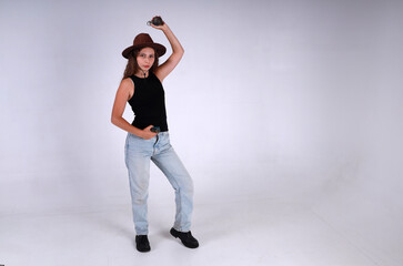 Young pretty woman in brown hat and blue jeans standing full length and holding american grenade
