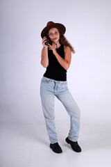 Young pretty woman in brown hat and blue jeans standing full length and holding american grenade