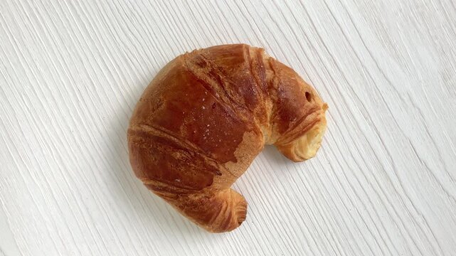 Homemade croissant rotating on white wooden table. 4K top view video