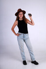 Young pretty woman in brown hat and blue jeans standing full length and holding american grenade