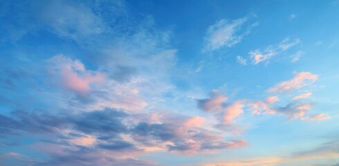 Vast, colorful sky with scattered clouds.  Soft pastel hues of pink and blue blend with patches of darker clouds