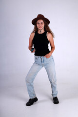 Young pretty woman in brown hat and blue jeans standing full length and holding american grenade