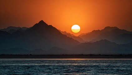 Sunset over a mountain range, reflecting on the water