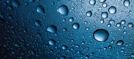 Close-up view of water droplets on a dark-blue surface.  The droplets are various sizes, and some are clustered together, creating a textured effect.  The image has a smooth, reflective quality