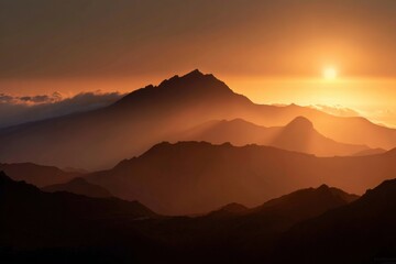 Golden sunset over a mountain range. Silhouettes of peaks bathed in warm light