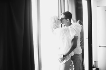 Young couple kissing in an embrace. young couple a guy and a girl of Caucasian ethnicity in white T-shirts embrace kissing