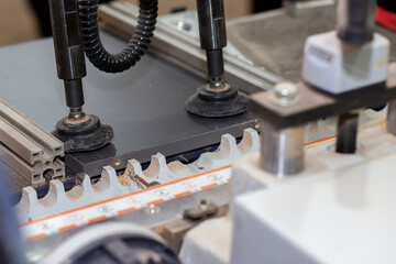 Drilling holes in a board with an industrial drill in a production furniture workshop