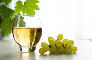 A glass of white wine with a bunch of green grapes on a light surface