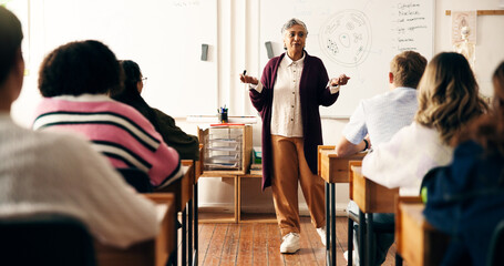 Educator, students or woman in classroom with whiteboard, speaking or listen in biology lesson. Knowledge, nature science or mature high school teacher in academy with teens, learning for future exam