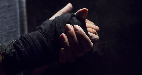 Fitness, hand and person in closeup with wrap, skin protection and preparation for MMA. Combat, training and athlete in studio with textile bandage, match safety and warm up on dark background.