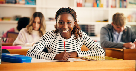 Excited, writing and portrait of teenager in classroom for learning, education or development....