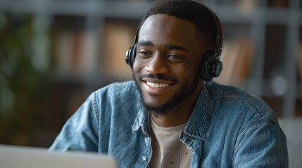 Joyful Young African-American Man with Headphones Engaged in Online Language Learning in a Modern Workspace
