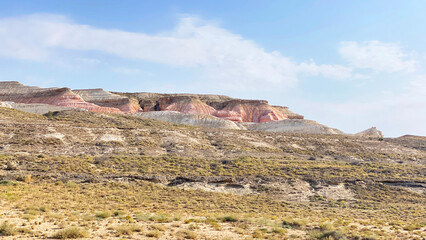 Amazing pink rocks somewhere in the vastness of Kazakhstan. Beautiful unusual nature. Colorful rocky hillside against a blue sky with white clouds