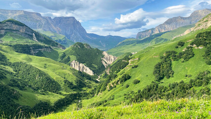 Obraz premium Aerial view of a picturesque green valley surrounded by high mountains, cliffs and ridges. Beautiful Azerbaijan. The valley is surrounded by greenery