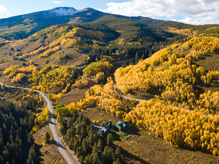 Beautiful yellow aspen forest during golden sunset in peak fall foliage with cottage on the hill at...
