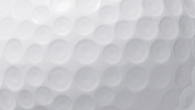 Extreme macro detail of a white golf ball surface, showcasing the iconic dimple pattern as an abstract textured background for sports concepts