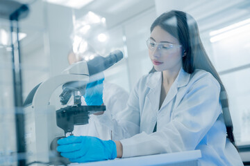 Research scientist examining samples under a microscope in a modern laboratory during the daytime