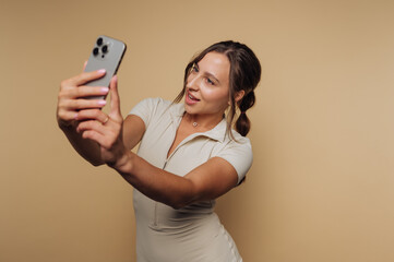 portrait of young woman joyfully takes a selfie with a smartphone, showcasing her playful side and...