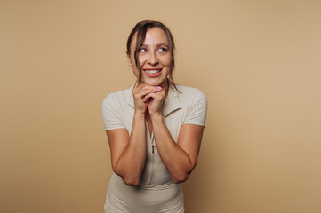 portrait of young cheerful woman clasps her hands, exhibiting a big smile, showcasing feelings of...