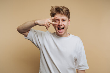 portrait of young happy man is playfully showing a peace sign, exuding a sense of fun and carefree...