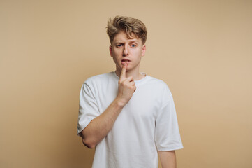 portrait of young man bites his finger while appearing lost in thought, capturing a moment of...