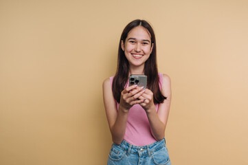 portrait of young woman flashes a bright smile while holding a smartphone, capturing a joyful...