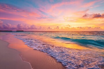 Obraz premium Tropical sunset over a tranquil beach. Golden-hued clouds paint the sky in vibrant colors. Ocean waves gently lap at the shore
