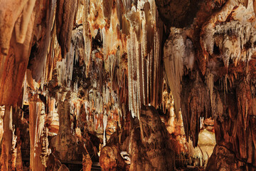 Panoramic view of stalactites and stalagmites in an artificially lit underground cave