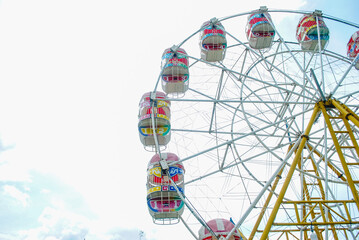 Ferris wheel with gondolas in children's play area, isolated in the sky
