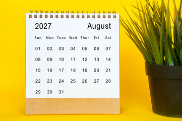 August 2027 calendar template on a yellow-framed background featuring organized date grid and plant...