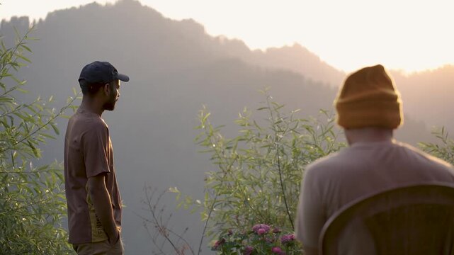 A young man sitting on the beach while another man takes a sunbath in the morning at Shoja, Manali, Himachal Pradesh, India.