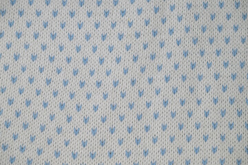 Close up of white knitted fabric with repeating light blue dot pattern