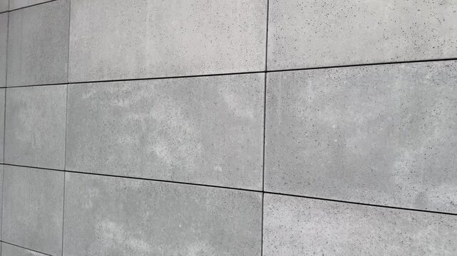 Close-up view of facade tiles crafted from architectural concrete, highlighting their smooth surface, modern texture, and geometric arrangement.