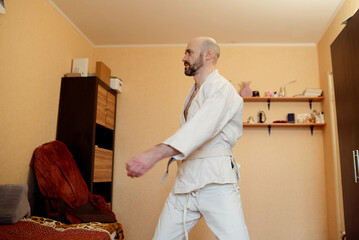 Man practices Tai Chi indoors, demonstrating calm focus and martial arts movements in a home...