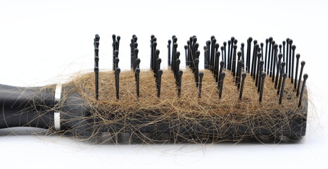 Black plastic hairbrush with blond hair. White background.